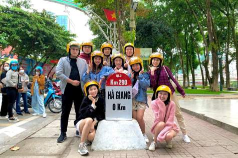 Tourists take commemorative photos at the first milestone when arriving in Ha Giang
